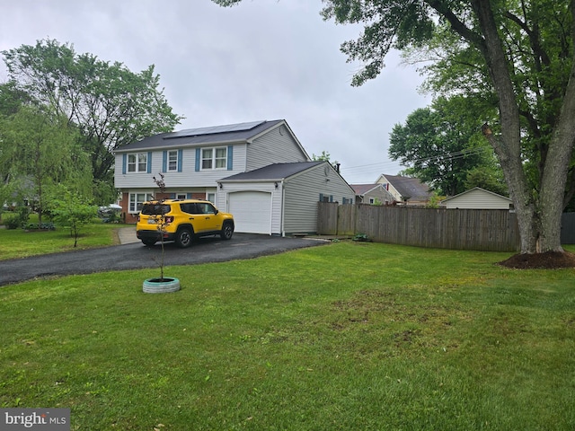 view of front facade featuring roof mounted solar panels, a garage, fence, a front yard, and driveway