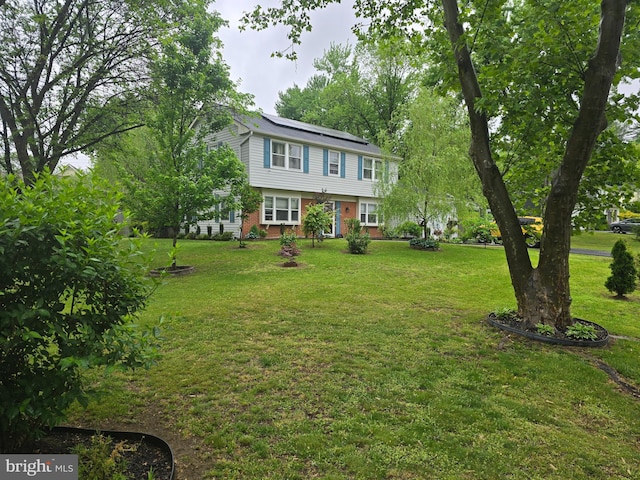 colonial-style house with solar panels, a front lawn, and brick siding
