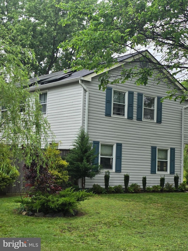 view of property exterior featuring solar panels and a lawn