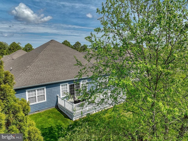 rear view of house with a yard, a wooden deck, and a shingled roof