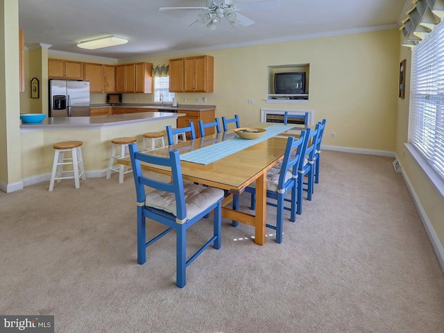 dining space featuring ornamental molding, light carpet, baseboards, and ceiling fan
