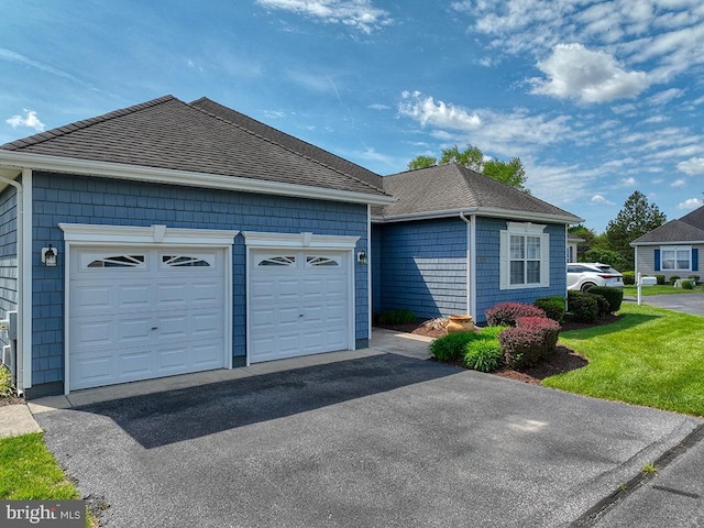 view of front of home with aphalt driveway, roof with shingles, and a garage