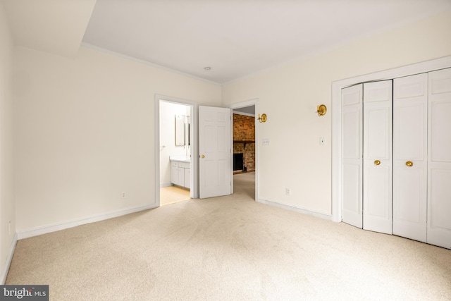 unfurnished bedroom with carpet flooring, connected bathroom, a closet, baseboards, and ornamental molding