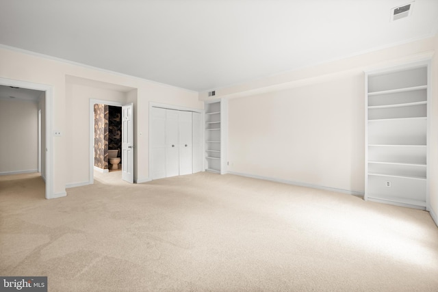 unfurnished bedroom featuring a closet, carpet, visible vents, crown molding, and baseboards