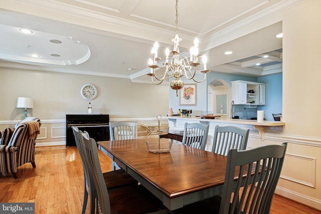 dining room with arched walkways, light wood-style floors, an inviting chandelier, and crown molding