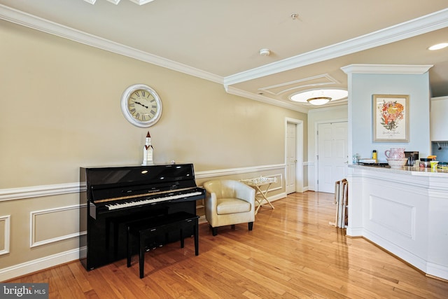 sitting room featuring light wood finished floors, a wainscoted wall, and ornamental molding