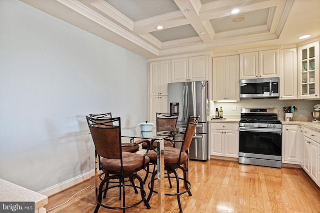 kitchen featuring light wood finished floors, beamed ceiling, light countertops, coffered ceiling, and appliances with stainless steel finishes