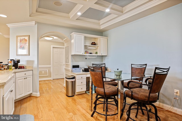dining room featuring ornamental molding, light wood-style floors, coffered ceiling, and beamed ceiling