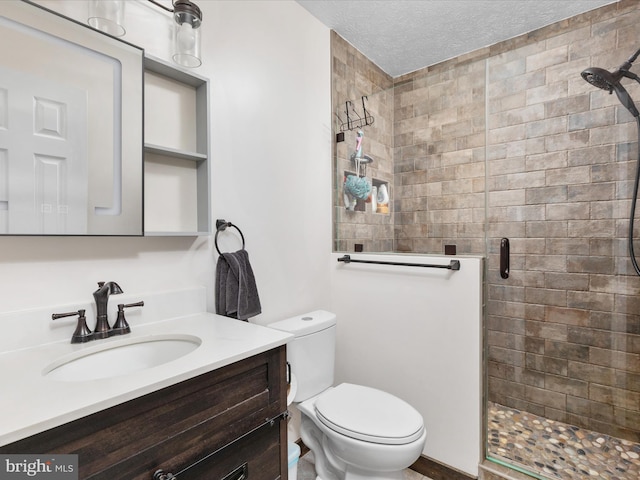full bath featuring a shower stall, toilet, vanity, and a textured ceiling