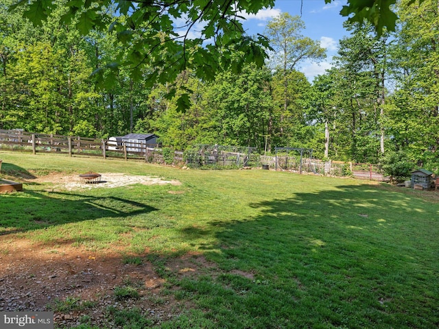 view of yard featuring a fire pit, a shed, and an outdoor structure