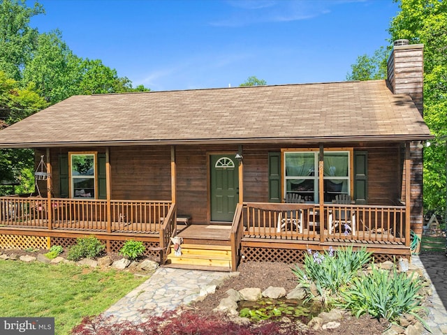 rustic home with a shingled roof, a chimney, and a porch
