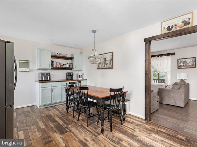 dining space featuring dark wood-style flooring, baseboards, a dry bar, and a chandelier