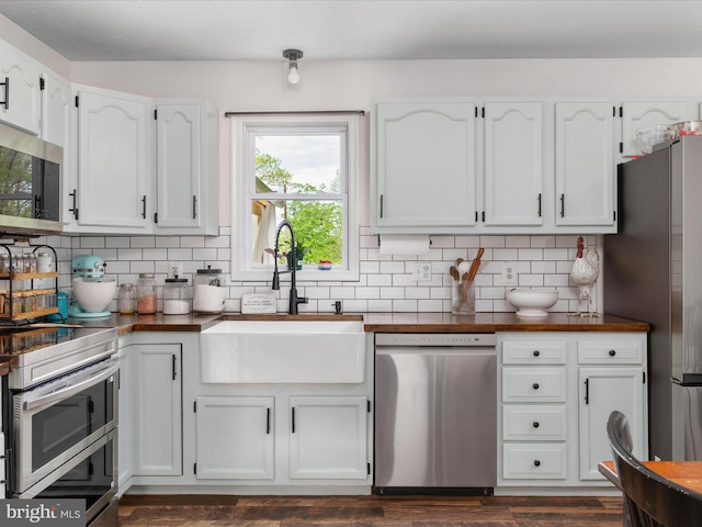 kitchen with appliances with stainless steel finishes, a sink, white cabinetry, and decorative backsplash