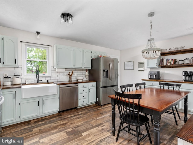 kitchen featuring stainless steel appliances, a sink, decorative backsplash, and dark wood-type flooring