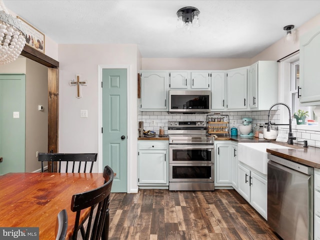 kitchen with stainless steel appliances, dark wood-type flooring, a sink, and decorative backsplash