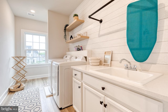 7679 Cross Creek Dr, Columbia, MD 21044 - laundry room featuring independent washer and dryer, light wood-type flooring, cabinet space, baseboards, and wooden walls