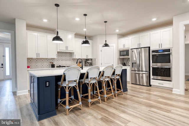 7679 Cross Creek Dr, Columbia, MD 21044 - kitchen with stainless steel appliances, light wood-style flooring, a kitchen bar, white cabinetry, and recessed lighting