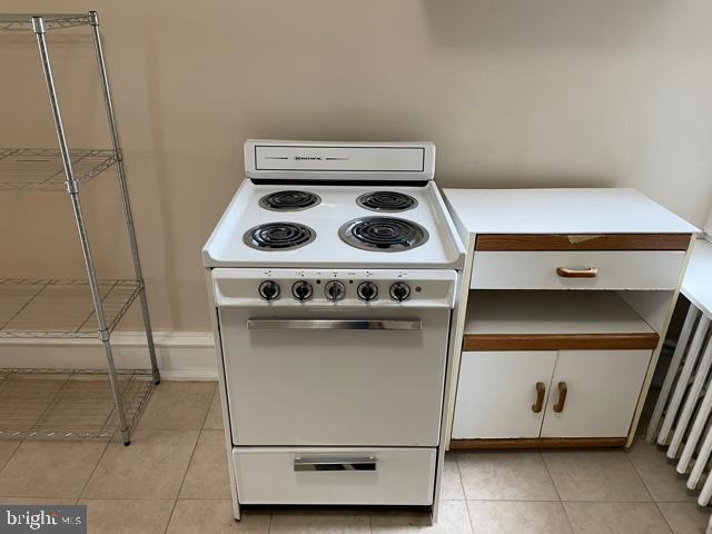 kitchen with white cabinets, white electric range, and light tile patterned floors