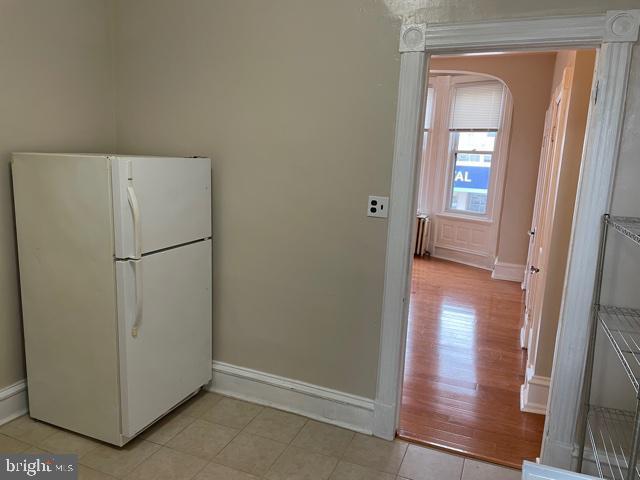 kitchen with freestanding refrigerator, baseboards, light wood-type flooring, and arched walkways