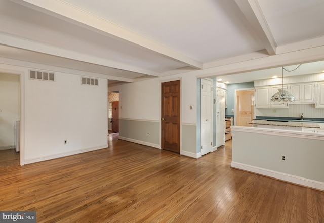 1149 Ollerton Rd, West Deptford, NJ 08066 - unfurnished living room featuring beamed ceiling, wood finished floors, a sink, and baseboards