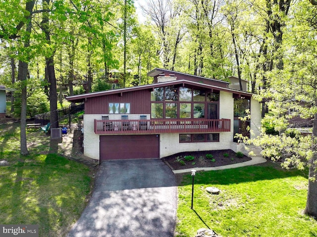 mid-century home with a front yard, aphalt driveway, and a garage