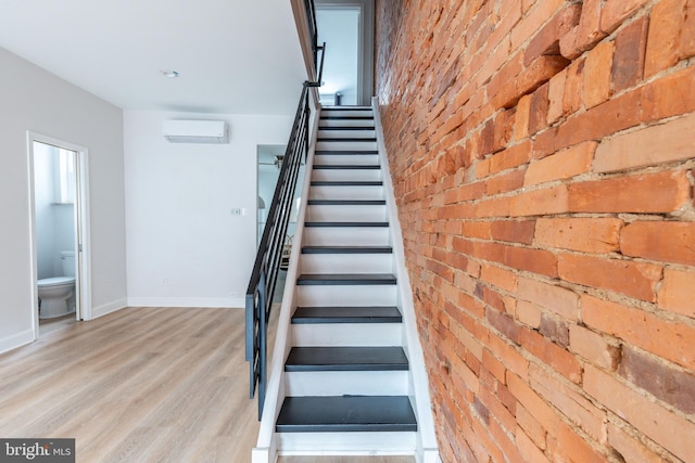 1545 S 19th St, Philadelphia, PA 19146 - stairway with baseboards, brick wall, a wall unit AC, and wood finished floors