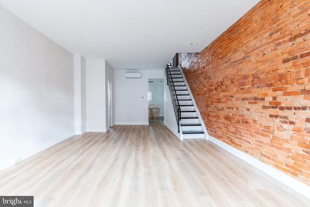 1545 S 19th St, Philadelphia, PA 19146 - unfurnished living room with a wall unit AC, baseboards, brick wall, wood finished floors, and stairway