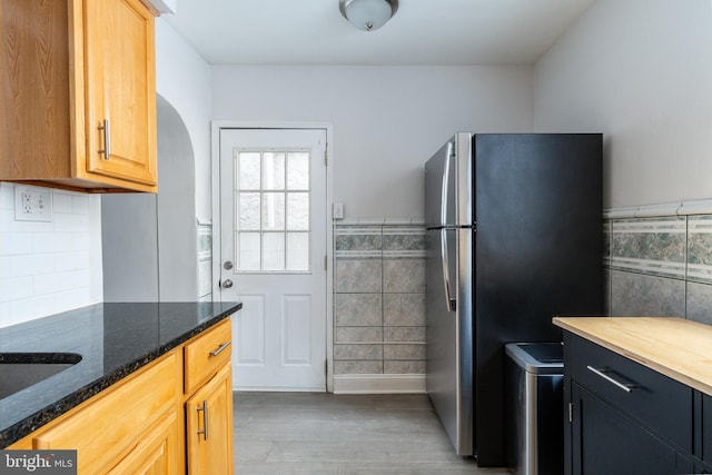 1545 S 19th St, Philadelphia, PA 19146 - kitchen featuring freestanding refrigerator, dark stone counters, tile walls, wainscoting, and light wood-style floors