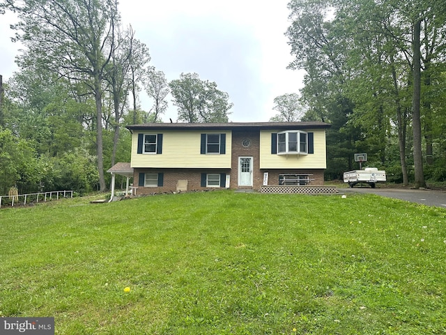split foyer home featuring driveway, brick siding, and a front yard