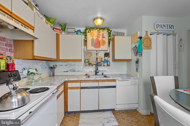 kitchen featuring under cabinet range hood, white appliances, a sink, decorative backsplash, and light countertops
