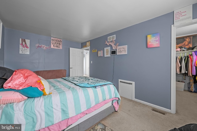 carpeted bedroom with a spacious closet, a closet, baseboards, and visible vents