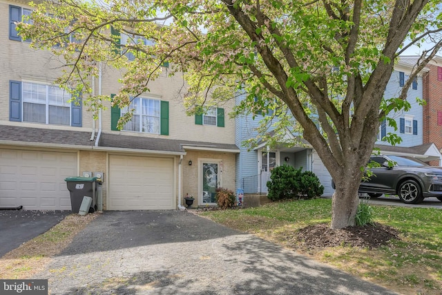 multi unit property featuring brick siding, driveway, and a garage