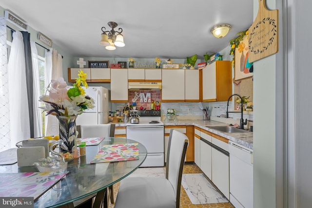 kitchen with a sink, white appliances, backsplash, under cabinet range hood, and light countertops