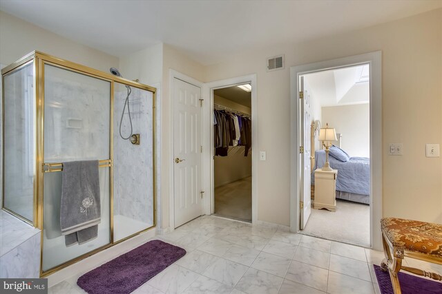 ensuite bathroom with a shower stall, marble finish floors, and a walk in closet