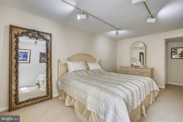 bedroom with track lighting, light colored carpet, and baseboards