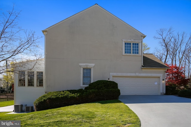 view of side of property with driveway, a lawn, a garage, and central AC