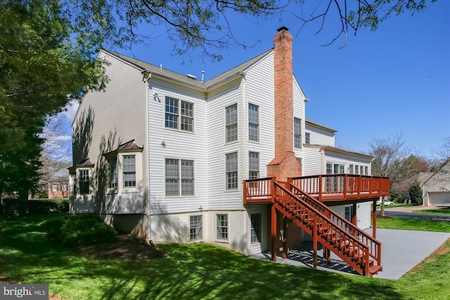 back of property with a chimney, stairs, a wooden deck, a lawn, and stucco siding