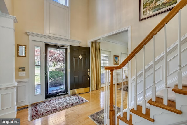 foyer entrance with a high ceiling, stairway, and light wood finished floors