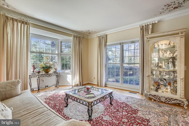 living room with plenty of natural light, ornamental molding, and wood finished floors