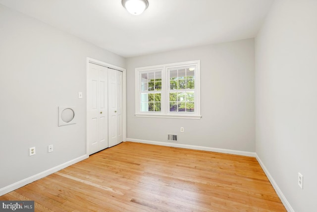unfurnished bedroom featuring light wood-type flooring, baseboards, and a closet
