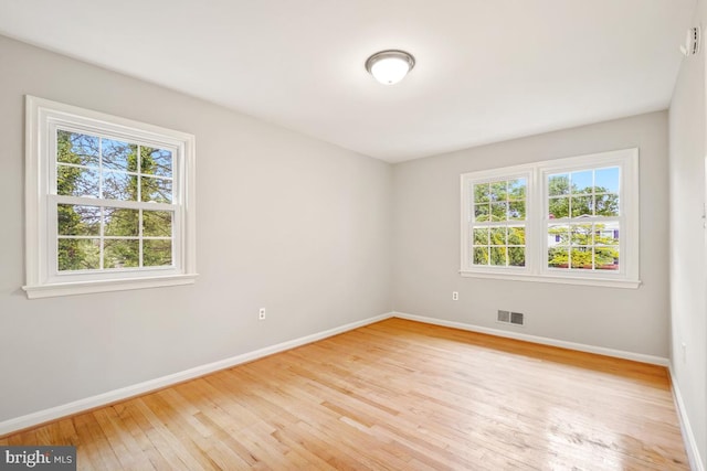 spare room with baseboards and light wood finished floors