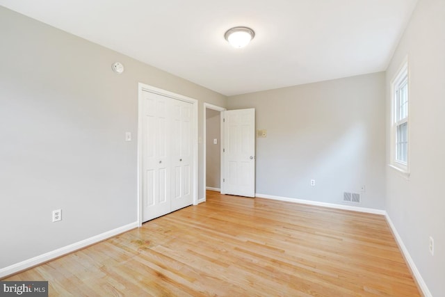 unfurnished bedroom with baseboards, light wood-style floors, and a closet