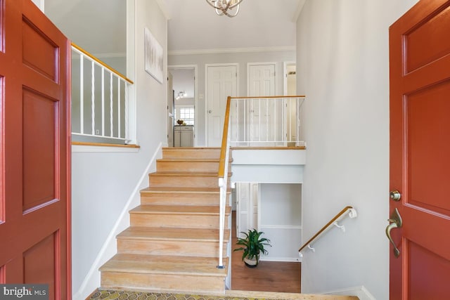 entrance foyer with ornamental molding, baseboards, and stairs
