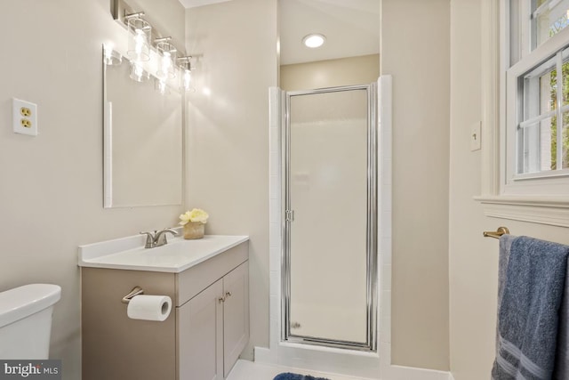 bathroom with a shower stall, toilet, and vanity