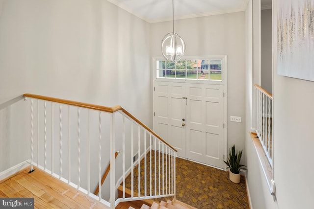 foyer entrance featuring a chandelier, crown molding, and wood finished floors