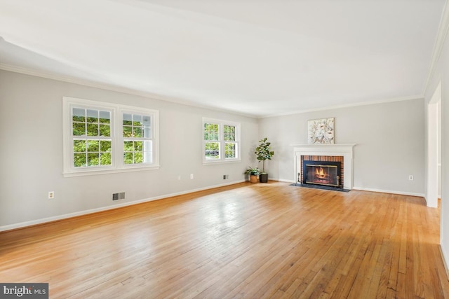 unfurnished living room featuring light wood-style flooring, crown molding, baseboards, and a fireplace