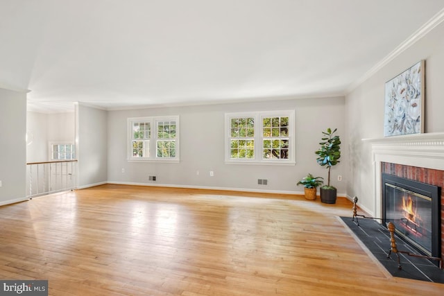 unfurnished living room with a fireplace with flush hearth, ornamental molding, wood-type flooring, and baseboards