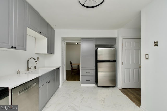 7313 Split Rail Ln, Laurel, MD 20707 - kitchen featuring appliances with stainless steel finishes, gray cabinetry, a sink, light marble finish flooring, and light countertops
