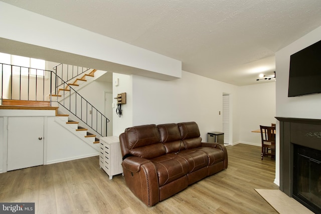 7313 Split Rail Ln, Laurel, MD 20707 - living room featuring light wood-style floors, stairway, a fireplace with flush hearth, baseboards, and a textured ceiling