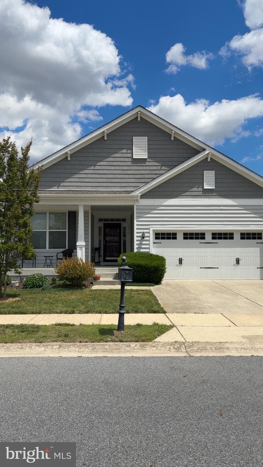 view of front of property with concrete driveway, an attached garage, and a porch